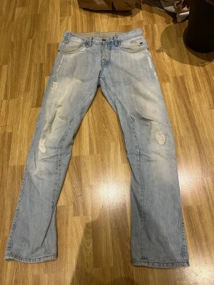 Ljusblå slitna jeans med raka ben - Ljusblå jeans med slitningar och lagade detaljer på knäna. Raka ben och klassisk femficksmodell. Jeansen har en avslappnad passform och är tillverkade i denim, perfekt för en casual look.