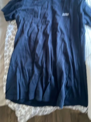 Mörkblå kortärmad t-shirt från BOSS - Snygg mörkblå t-shirt från BOSS med diskret logga på bröstet. Klassisk passform och rund halsringning. Perfekt till jeans eller shorts för en clean och enkel stil.