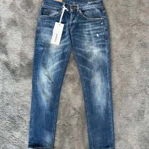 Dondup george - Snygga blå jeans från Dondup med slitna detaljer. Klassisk femficksmodell med orange sömmar och diskret logga bak. Jeansen har rak passform och är tillverkade i mjukt bomullsjeans.