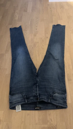 Mörkblå jeans från Dr. Denim - Säljer ett par mörkblå jeans från Dr. Denim med klassisk femficksdesign och raka ben. Jeansen har en snygg tvättad look och är tillverkade i stretchigt denimtyg för extra komfort. Perfekta för en avslappnad och trendig stil.