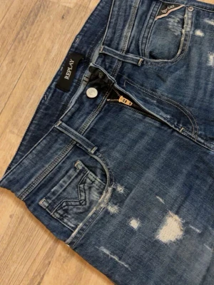 Blå slitna jeans från Replay limited - Säljer ett par blå skinny jeans från Replay med slitningar och tvättade detaljer. Jeansen har klassisk femficksmodell, dragkedjegylf och snygga slitna partier på både fram- och baksida. Perfekta för en trendig och avslappnad look. Finns ej längre alltså limiterade!
