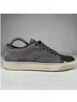 Lanvins - Stilrena sneakers i grå mocka med mörkgrå lackad tå och matchande snörning. Skon har en vit sula och diskreta sömmar för en clean look. Perfekt för dig som gillar en mix av material och vill ha något unikt till vardagslooken.