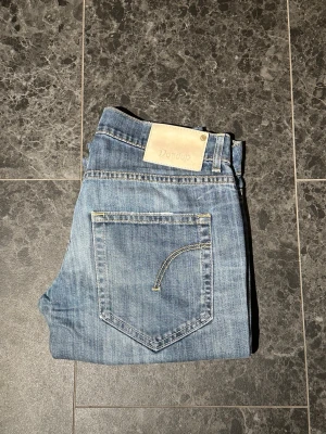 Ljusblå jeans från Dondup - Snygga ljusblå jeans från Dondup med klassisk femficksmodell och kontrastsömmar. Jeansen har en patch med logga bak i midjan. Jeansen är i storlek 29, och i ett mycket bra skick. Bara att höra av sig vid eventuella frågor!