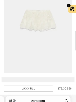 Vit kortkjol med spets från Zara - Supersöt vit kortkjol från Zara med spetsdetaljer och vågig kant. Kjolen har en romantisk känsla och passar perfekt till sommarens outfits. Lätt och luftig design som ger en feminin look.