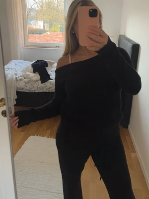 Svart off shoulder stickad tröja - Säljer en svart stickad tröja med off shoulder-design och långa ärmar. Tröjan har en avslappnad passform och ribbade muddar vid ärmsluten. Perfekt för dig som gillar en trendig och bekväm stil. 