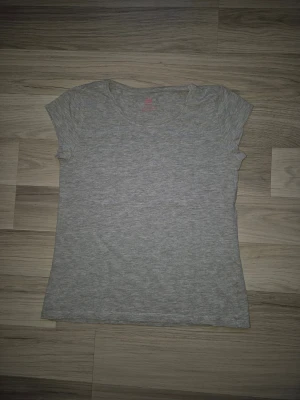 Ljusgrå basic t-shirt - En enkel och stilren ljusgrå t-shirt med rund hals och korta ärmar. Tillverkad i mjuk bomull som känns skön mot huden. Perfekt att matcha med jeans eller shorts för en clean look.