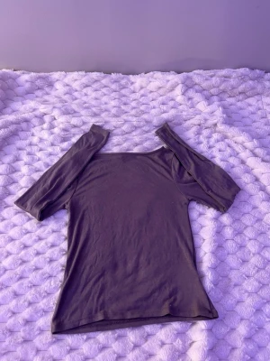 Svart offshoulder topp - Trendig svart offshoulder topp med smal passform och korta ärmar. Perfekt att styla med jeans eller kjol för en cool och enkel look. Tillverkad i mjukt bomullsmaterial som känns skönt mot huden.