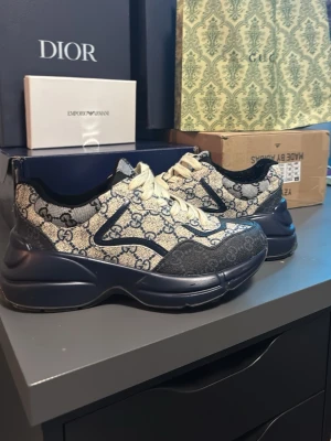 Gucci rhython skor helt nya passade inte min storlek. - Detta är ett par Gucci rhython skor i mörkblå beige färg skick 10/10 har aldrig andvänt utomhus. Inte en skroma perfekta för sintern och sommarn de är i storlek 41 men passar 41,5