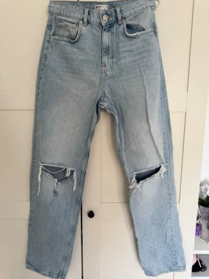 Ljusblåa ripped jeans från Gina Tricot - Säljer ett par ljusblåa jeans från Gina Tricot med raka ben och slitningar på båda knäna. Klassisk femficksmodell och hög midja. Perfekta för dig som gillar en avslappnad och trendig look. Skriv gärna om ni har frågor eller vill ha fler bilder!!