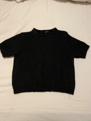 Svart stickad tröja  - En enkel svart stickad tröja från Lager 157 med korta ärmar och rund hals. Säljer denna då jag har ganska lång överkropp och den sitter lite kort på mig. Den är använd max 4 gånger. 