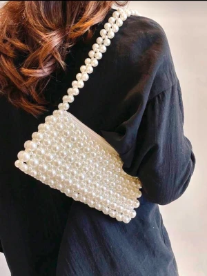  pärlbeströdd handväska - Superfin handväska helt täckt av vita pärlor med matchande pärlhandtag. Väskan har en rektangulär form och stängs med dragkedja. Perfekt accessoar för att lyfta vilken outfit som helst med en elegant touch.