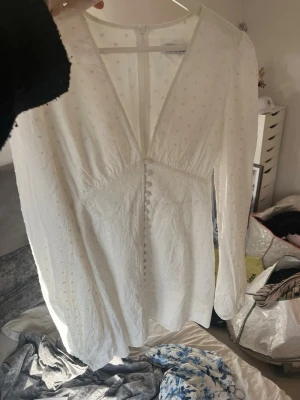 Vit  Adoore adooreklänning  - Supersnygg vit klänning från Adoore med diskret prickigt mönster, v-ringning och knappar framtill. Långärmad modell i lätt, luftig kvalitet med omlottkänsla. Perfekt för sommarens alla tillfällen!