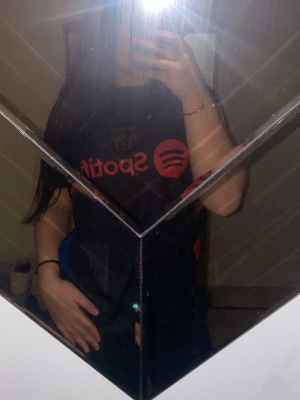 FC Barcelona matchtröja svart/röd - Säljer en svart FC Barcelona matchtröja med röda detaljer och tryck, inklusive Spotify-logga på bröstet och La Liga-märke på ärmen. På ryggen står det 'Lamine Yamal' och nummer 19. Perfekt för dig som älskar fotboll och Barca!