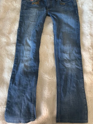 Blå bootcut jeans från Diesel - Säljer ett par blå bootcut jeans från Diesel med snygg slitning och broderad detalj vid fickan. Midja: 40 cm längd 95 cm. Passar någon som är 160 nog