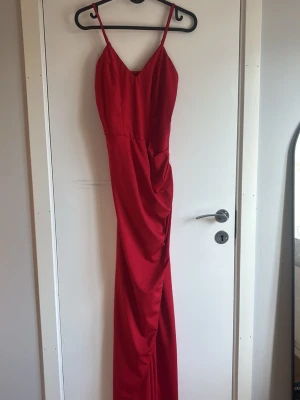 Röd långklänning med smala axelband och slits - Kan skicka bild hur den ser ut på vid intresse . 