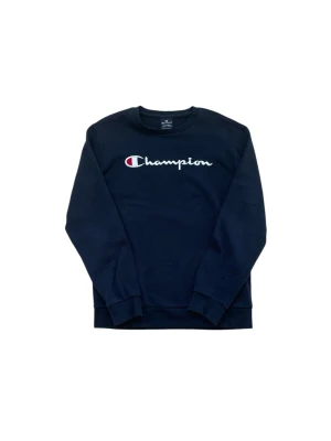Mörkblå sweatshirt från Champion - Mörkblå sweatshirt från Champion med klassisk logga broderad i vitt, rött och blått på bröstet. Tröjan har rund halsringning, långa ärmar och ribbade muddar vid ärmslut och nederkant. Perfekt för en avslappnad och sportig stil.