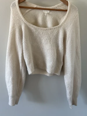 Krämvit stickad croppad tröja H&M - Säljer en krämvit stickad tröja från H&M, med rundad urringnin. Tröjan har långa ärmar och ribbstickad struktur. 