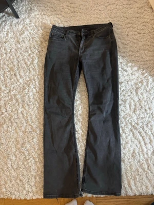 Lågmidjade bootcut jeans - Säljer ett par lågmidjade svarta jeans från weekday med klassisk femficksdesign. Jeansen har normal/låg midja och stängs med dragkedja och knapp. Materialet är denim och färgen är en tvättad svart nyans. Perfekta för en avslappnad och stilren look.