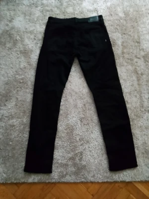 Svarta jeans från BOSS Black Label - Säljer ett par svarta jeans från BOSS med klassisk femficksmodell och diskret logga på bakfickan. Jeansen har rak passform och är tillverkade i ett mjukt denimtyg som sitter snyggt. Perfekta för dig som gillar stilrena och tidlösa Jeans 