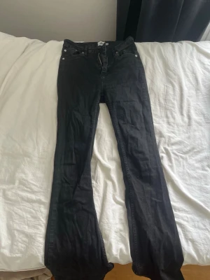 Svarta bootcut jeans - Säljer ett par svarta bootcut jeans med klassisk femficksdesign och normal midja. Jeansen har en snygg utsvängd passform nedtill och är tillverkade i ett stretchigt denimtyg som sitter bekvämt. Perfekta för dig som gillar en tidlös och trendig look.