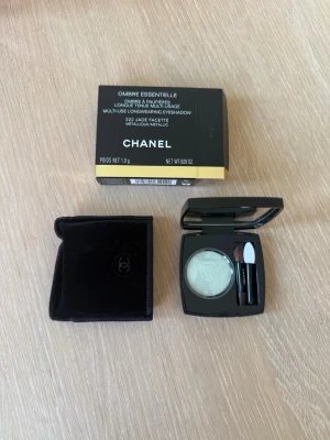 Chanel grön metallisk ögonskugga - Snygg metallisk ögonskugga från Chanel i nyansen 222 Jade Facette. Kommer i en elegant svart dosa med spegel och applikator, samt en svart sammetsficka. Perfekt för dig som vill ha en lyxig touch till din sminkning. Helt oanvänt.