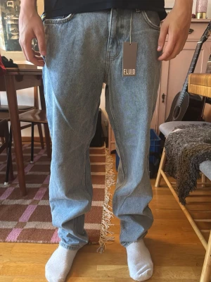 Baggy ljusblå jeans från Fluid - Baggy jeans i ljusblå denim från Fluid. Klassisk femficksmodell med raka ben och hög midja. Jeansen har en avslappnad passform och är tillverkade i bomull. Perfekta för en chill och trendig look.