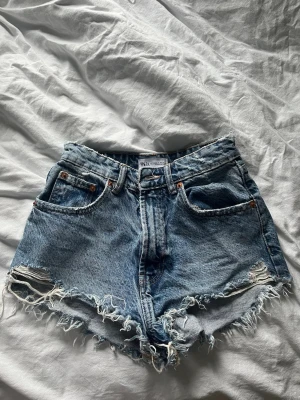 Blå denimshorts från Zara - Säljer ett par blå denimshorts från Zara i storlek 34. 
