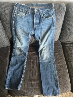 Blå raka jeans med fem fickor - Klassiska blå jeans med rak passform och fem fickor. Jeansen har en knappgylf, kontrastsömmar och subtila slitningar framtill för en avslappnad look. Tillverkade i denim med en tidlös tvätt och normal midja.