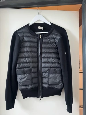Moncler cardigan  - Snygg svart cardiganjacka från Moncler, vet ej om den är äkta då jag fått den i present och inte har något kvitto, lappen i nacken är lös annars är den i felfritt skick 
