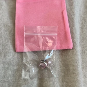 Pandora silverberlock med rosa sten - Säljer en snygg liknande Pandora-berlock i silver med en facetterad ljusrosa sten. Perfekt att sätta på ditt armband för en extra touch av färg och stil. Kommer med en rosa påse för förvaring.