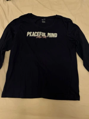 Mörkblå långärmad pyjamas topp  - Mörkblå långärmad topp från Esmara med trycket 'Peaceful Mind' framtill i vit och ljusblå text. Rund halsringning och mjukt material som känns skönt mot huden. Perfekt för en chill och avslappnad stil.
