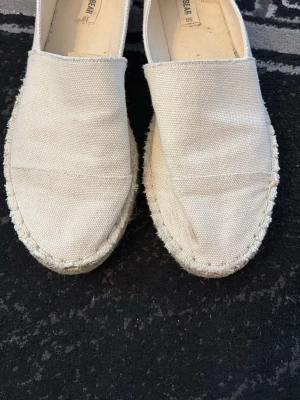 Beige espadrilles från Pull&Bear - Säljer ett par beige espadrilles från Pull&Bear. Skorna är i canvas med klassisk rund tå och grov sula i repimitation. Perfekta för en chill och avslappnad stil. Lätta att matcha med det mesta och superbekväma att ha på sig.