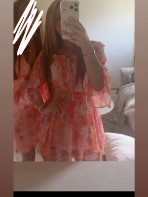 Kort rosa och orange omlottklänning - Jättefin rosa/orange kort klänning. Klänningen har som ett ”skärp” som man även kan välja att ta bort om man vill! Klänningen är endast använd en gång därför nyskick. Passar storlek Xs/S. Skriv gärna vid frågor💕