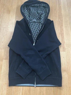 Svart hoodie med mönstrat foder D I O R - Snygg svart hoodie med huva och ett unikt svartvitt mönstrat D I O R