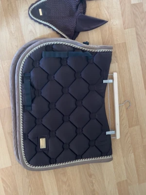 Brunt schabrak och huva med mönster - Säljer ett brunt schabrak med matchande huva till häst. Huva nästan aldrig använt, schabrak fint skick. Storlek full