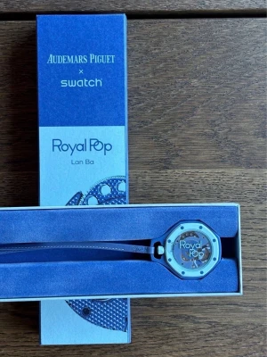 Blå Audemars Piguet x Swatch Royal Pop - Snygg blå klocka från Audemars Piguet x Swatch Royal Pop-kollektionen. Klockan har en åttakantig boett, blå urtavla med AP x Swatch-logga och vita detaljer. Snygg och modern design med sportig känsla. Levereras i originalförpackning.
