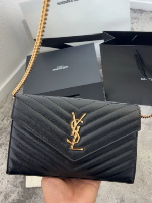 Ysl Classic Cassandre  - Saint Laurent Classic Cassandre Wallet on Chain (äldre modell)  Säljer min Saint Laurent Classic Cassandre Wallet on Chain i mycket fint skick. Väskan är den äldre modellen med 20 kortfack, till skillnad från den nuvarande modellen som har 10 kortfack.  Väskan har vårdats regelbundet och är behandlad med läderkräm för att hålla lädret mjukt och välbevarat.  Detta medföljer:  *Originalbox * Dust bag * Original shoppingpåse Digitalt originalkvitto från Saint Laurent * Digital vinted köpbekräftelse