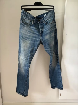G star 3301 tapered - Säljer ett par klassiska blå jeans med raka ben och snygga slitningar framtill. Jeansen har fem fickor, normal midja och är gjorda i denim. Perfekta för en avslappnad och trendig look.