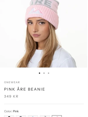 Rosa Åre mössa med tofs från Onewear - Säljer en rosa stickad mössa från Onewear med grå detaljer och stor grå tofs. Mössan har uppvikt kant och ett broderat bergsmotiv framtill samt texten 'ÅRE' i grått. Perfekt för dig som vill ha en snygg accessoar med vintervibbar.