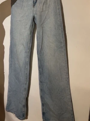 Ljusblå raka jeans - Säljer ett par ljusblå jeans med rak passform och hög midja. Jeansen har klassisk femficksdesign och är tillverkade i denim. Perfekta för dig som gillar en avslappnad och trendig stil.