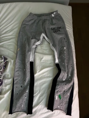 Grå mjukisbyxor Gallery Dept. - Grå mjukisbyxor från Gallery Dept. med svart och vit kontrast längs benen och färgstänk i vitt, grönt och gult. 