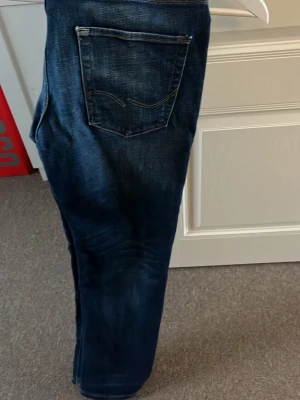Mörkblå jeans Comfort/Mike - Snygga mörkblå jeans Jack&Jons. Jeansen har en rak passform och coola slitningar på benen. Perfekta för en avslappnad och trendig look.