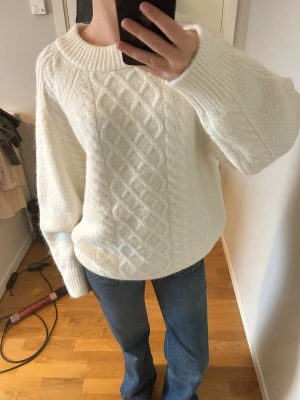 Vit stickad tröja från Gina Tricot - Mysig vit stickad tröja från Gina Tricot i storlek M. Tröjan har ett snyggt flätmönster framtill och på ärmarna, samt bred ribbad kant vid hals och muddar. Passformen är loose och den har långärmade ärmar. Perfekt för kyliga dagar. I nyskick 🤍