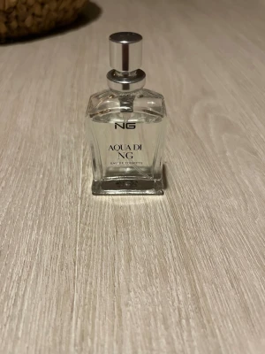 Aqua di NG Eau de Toilette - Aqua di NG Eau de Toilette är en parfym med fräsch och modern känsla. Flaskan är transparent med silverfärgad kork och har en stilren, fyrkantig form. Förpackningen är grå med subtilt mönster och eleganta detaljer. Perfekt för dig som gillar klassiska dofter.