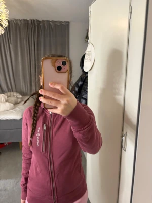 Vinröd hoodie från Sail Racing - Säljer en vinröd hoodie från Sail Racing med dragkedja och huva. Hoodien har en bröstficka med dragkedja och logotyp på framsidan. Materialet är mjukt och bekvämt, perfekt för chill dagar. Passar dig som gillar sportiga och stilrena plagg.