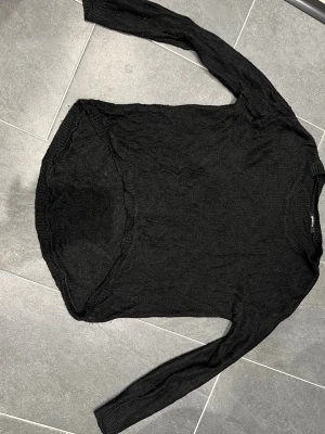 Svart stickad tröja Gina Tricot - Svart stickad tröja från Gina Tricot med rund halsringning och långa ärmar. Tröjan har en något längre bakdel och ribbstickade muddar vid halsen. Perfekt basplagg till garderoben och enkel att styla.