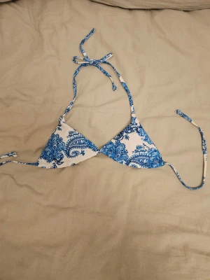 Blåvit trekantsbikini med paisleymönster - Jätte fin bikini överdel i vit blått mönstrat tyg men som tyvär va för liten och jag köpte på vinted