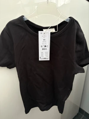 Svart topp Gina Tricot - Svart topp/t-shirt från Gina Tricot. Helt ny, aldrig använd. Storlek XS. Ordinarie pris 160 kr.  