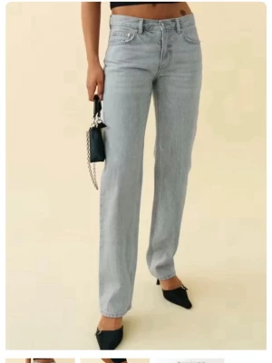 Ljusgrå raka jeans med hög midja - Säljer ett par ljusgrå jeans med rak passform och låg midja. Jeansen har klassisk femficksdesign och stängs med knapp och dragkedja. Perfekta för en avslappnad och trendig look.