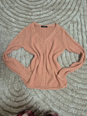 Rosa stickad tröja från Vila - Mysig stickad tröja i gammaldags rosa från Vila med flätstickat mönster framtill och längs ärmarna. Tröjan har v-ringning, långa ärmar. Skriv gärna om prisförslag❤️